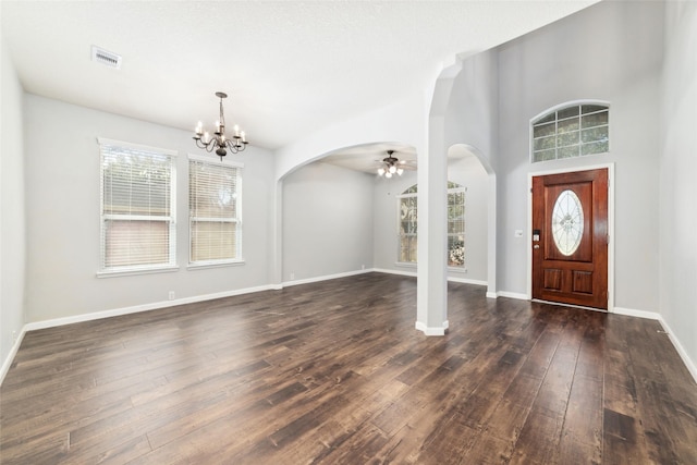 entrance foyer with visible vents, baseboards, ceiling fan with notable chandelier, arched walkways, and dark wood-style flooring