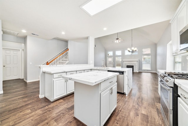 kitchen with a sink, a kitchen island, open floor plan, white cabinetry, and stainless steel appliances