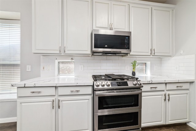 kitchen featuring white cabinetry, light stone countertops, tasteful backsplash, and stainless steel appliances