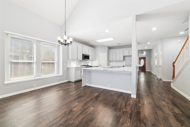 kitchen featuring a wealth of natural light, stainless steel microwave, dark wood-type flooring, and a notable chandelier