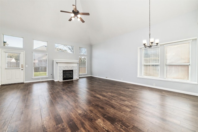 unfurnished living room featuring ceiling fan with notable chandelier, dark wood-style floors, baseboards, and high vaulted ceiling