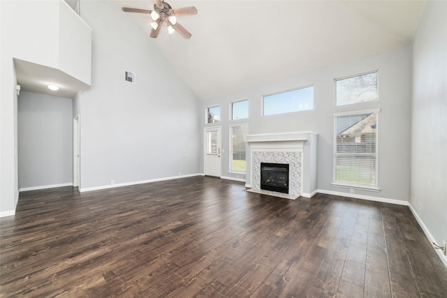 unfurnished living room featuring a wealth of natural light, dark wood finished floors, baseboards, and ceiling fan