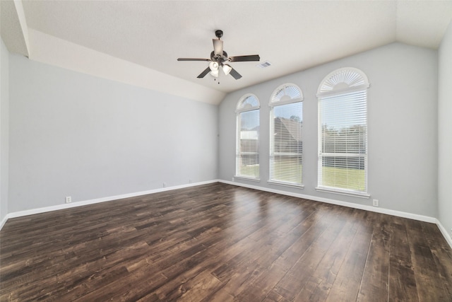 empty room featuring a ceiling fan, visible vents, baseboards, lofted ceiling, and dark wood-style flooring