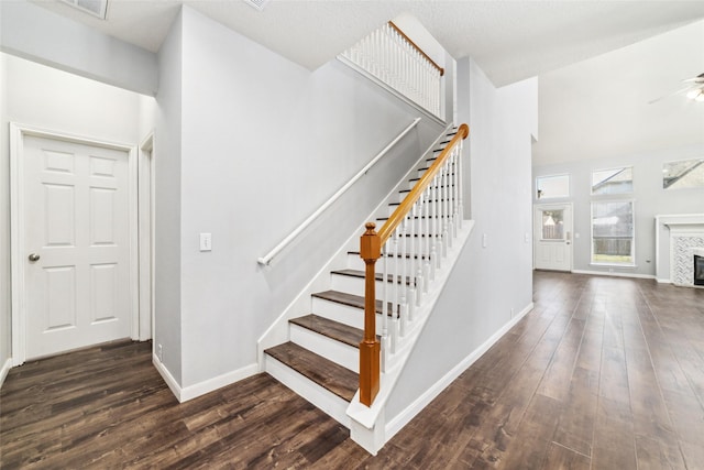 stairway with baseboards, hardwood / wood-style floors, and a tile fireplace