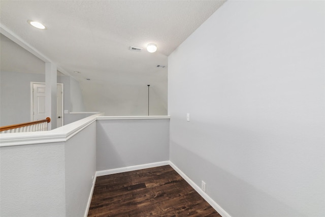 hall with an upstairs landing, visible vents, baseboards, and wood finished floors