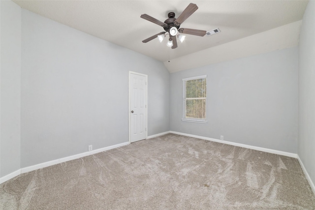 carpeted empty room with lofted ceiling, a ceiling fan, visible vents, and baseboards