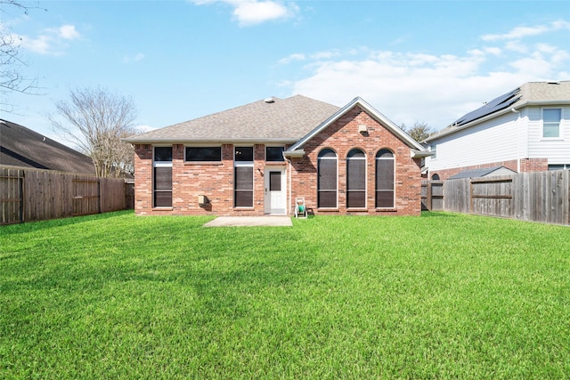 back of house with a lawn, brick siding, and a fenced backyard