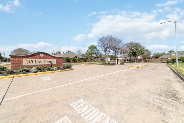 view of street featuring street lights, traffic signs, curbs, and a gated entry