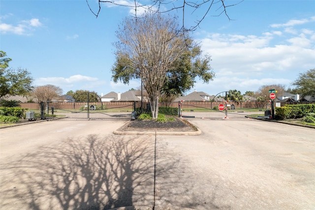 view of street featuring traffic signs, curbs, a gated entry, and a gate