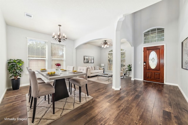 dining space featuring dark wood finished floors, visible vents, arched walkways, and baseboards