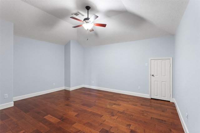 spare room featuring visible vents, dark wood-type flooring, baseboards, lofted ceiling, and ceiling fan