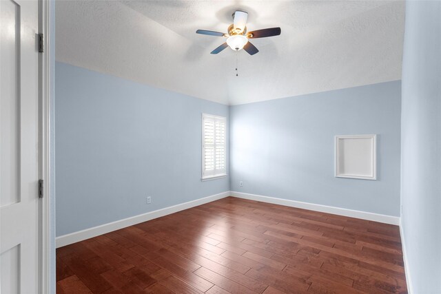 unfurnished room with wood finished floors, a ceiling fan, baseboards, vaulted ceiling, and a textured ceiling