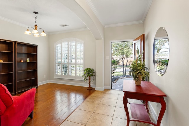 entryway featuring visible vents, baseboards, a notable chandelier, and crown molding