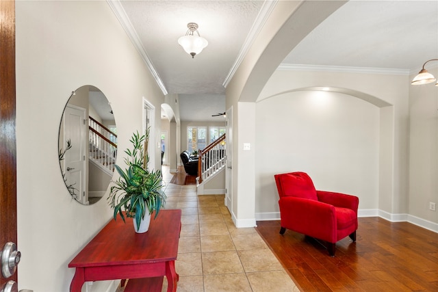 entryway featuring arched walkways, stairs, and crown molding