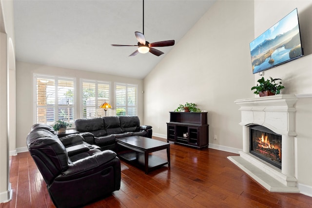 living area featuring hardwood / wood-style floors, baseboards, a lit fireplace, and ceiling fan