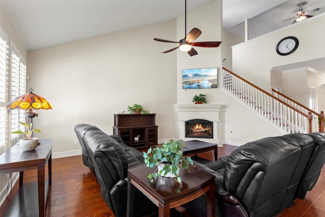 living room with baseboards, dark wood-style flooring, and a ceiling fan