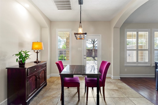 dining space featuring arched walkways, visible vents, baseboards, and an inviting chandelier