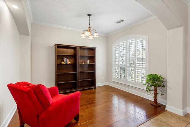 sitting room featuring visible vents, wood finished floors, a chandelier, and crown molding