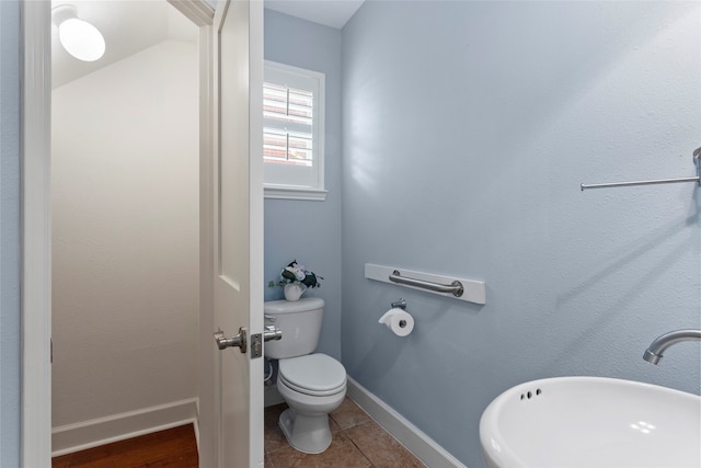 bathroom with tile patterned floors, baseboards, toilet, and a sink