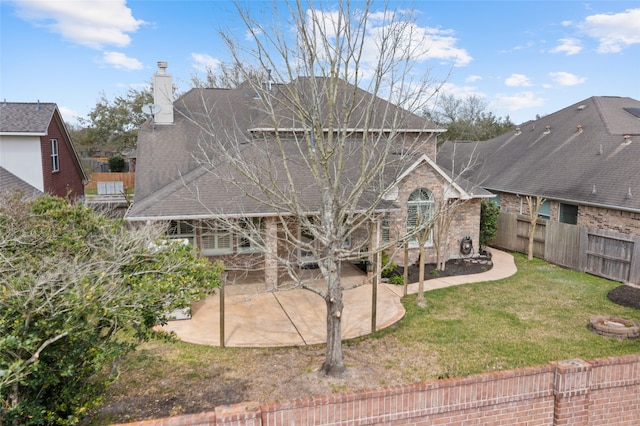 back of house with a shingled roof, fence, a chimney, a yard, and a patio area