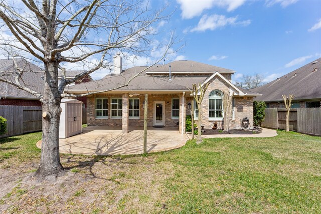 rear view of property with brick siding, a lawn, an outdoor structure, a fenced backyard, and a patio