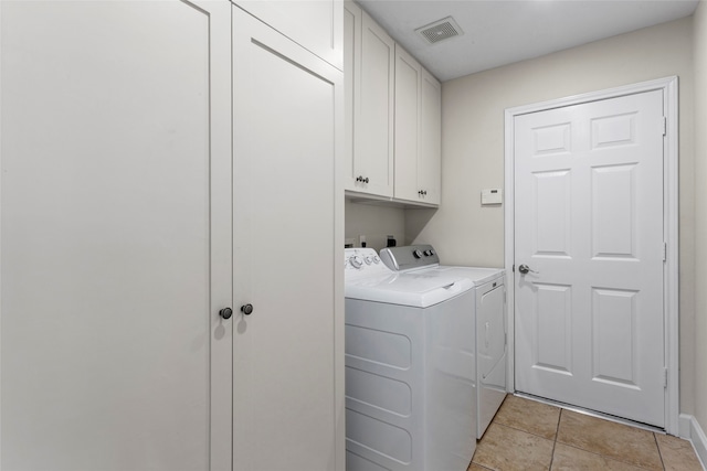 washroom featuring light tile patterned flooring, visible vents, cabinet space, and separate washer and dryer