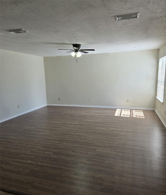 spare room featuring a ceiling fan, a textured ceiling, visible vents, baseboards, and dark wood-type flooring