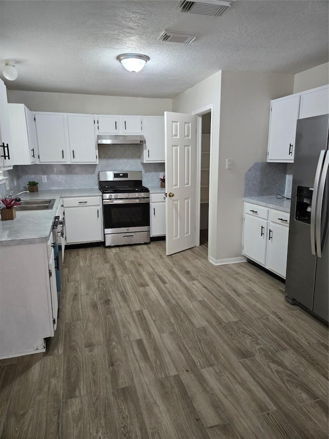 kitchen with a sink, visible vents, light countertops, dark wood-style floors, and appliances with stainless steel finishes