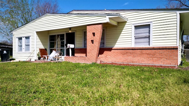 view of front of house with brick siding, covered porch, and a front yard