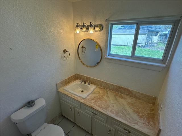 bathroom with toilet, vanity, and a textured wall