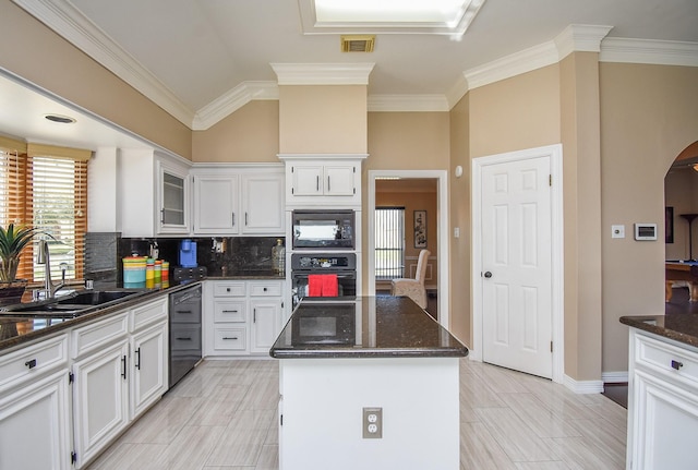 kitchen featuring visible vents, a kitchen island, dark stone counters, a sink, and black appliances