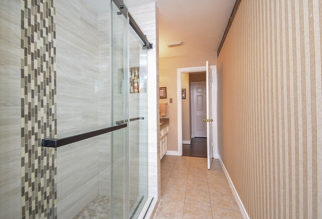 full bath featuring tile patterned flooring, visible vents, a shower stall, baseboards, and vanity