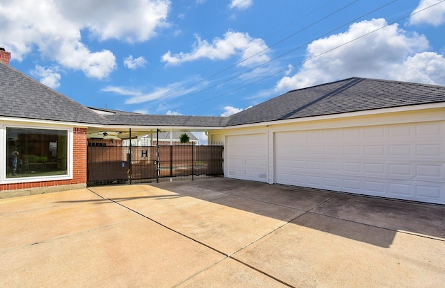 garage with concrete driveway, a ceiling fan, and fence