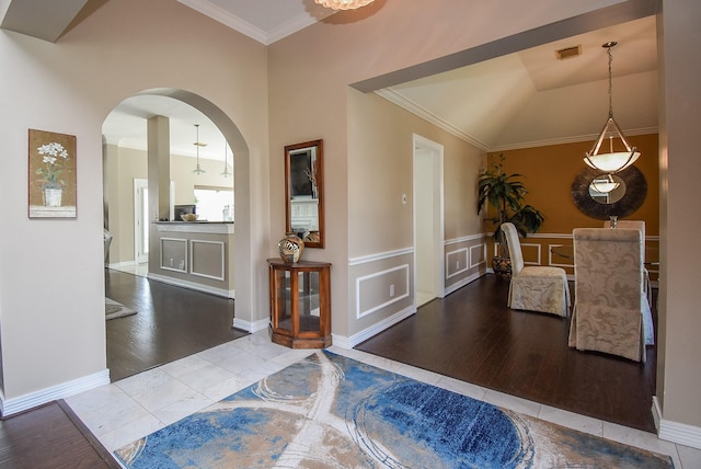 tiled entryway with crown molding, a decorative wall, arched walkways, and visible vents