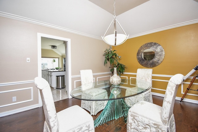 dining area with a decorative wall, wood finished floors, and vaulted ceiling