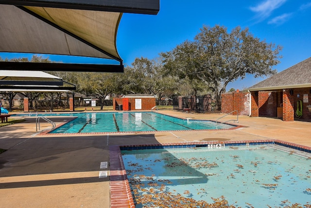 pool with an outdoor structure, a patio, and fence