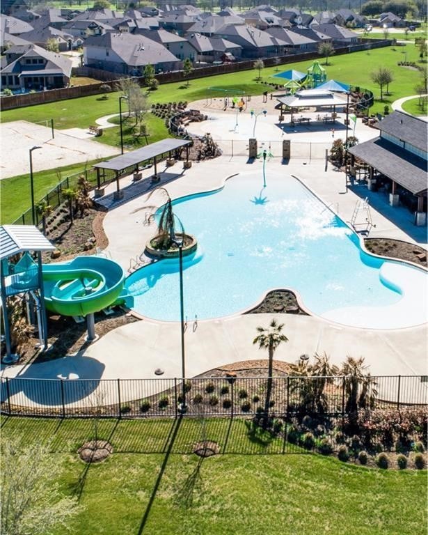 view of swimming pool with fence, a residential view, and a lawn