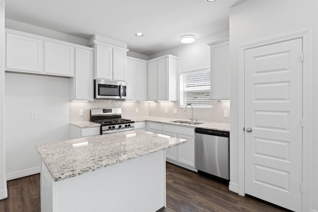 kitchen featuring a sink, stainless steel appliances, a kitchen island, and white cabinetry