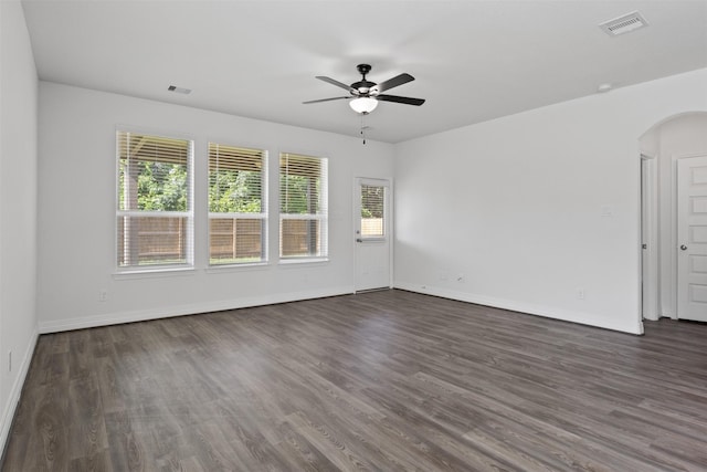 spare room featuring visible vents, arched walkways, dark wood-style floors, and a ceiling fan