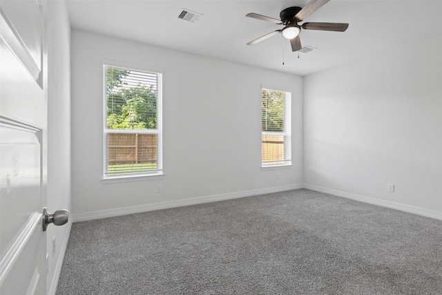 carpeted spare room with visible vents, baseboards, and a ceiling fan