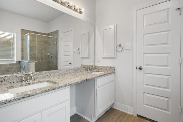 bathroom with a sink, wood finished floors, a stall shower, and double vanity