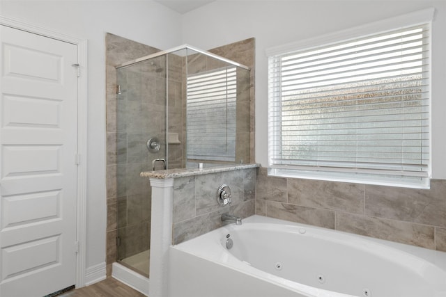 full bathroom featuring plenty of natural light, a stall shower, a jetted tub, and wood finished floors