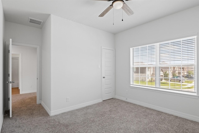 carpeted empty room featuring visible vents, baseboards, and ceiling fan