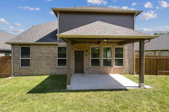 rear view of house featuring fence, a lawn, a ceiling fan, and a shingled roof