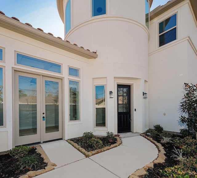 view of exterior entry featuring french doors and stucco siding