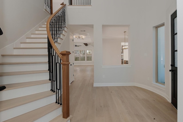 entryway with an inviting chandelier, stairway, wood finished floors, and baseboards