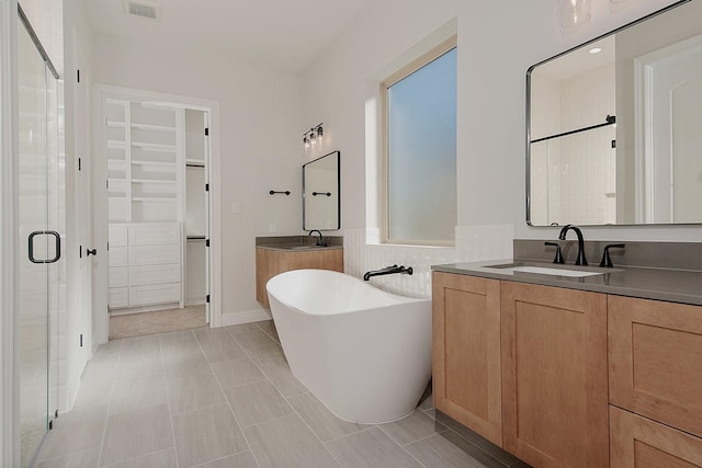 bathroom featuring visible vents, a sink, a shower stall, a soaking tub, and a spacious closet