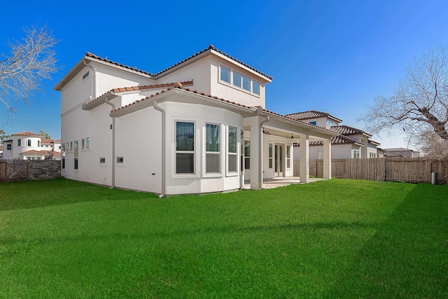 rear view of house featuring a fenced backyard, stucco siding, a tiled roof, a patio area, and a lawn