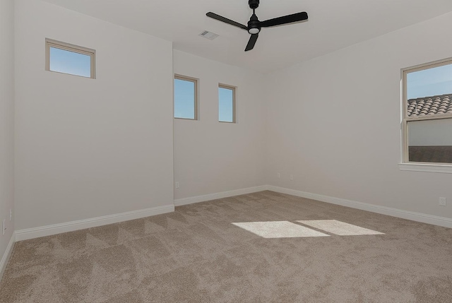 carpeted empty room featuring a ceiling fan, visible vents, and baseboards