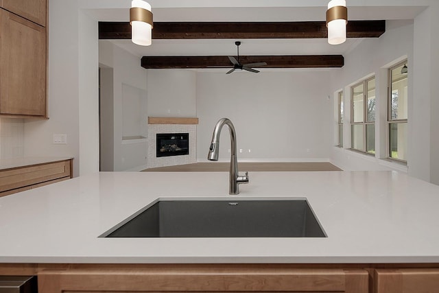 kitchen featuring light countertops, a ceiling fan, open floor plan, and a sink